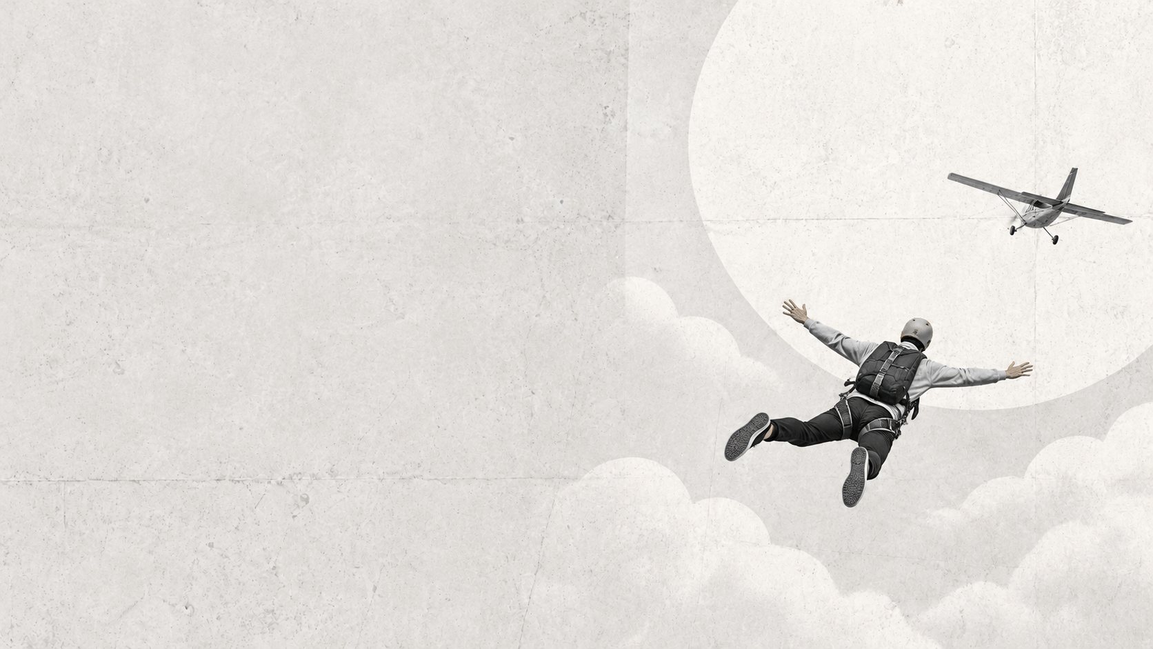 A skydiver in an ochre helmet in free fall above the clouds, a small plane flying off behind him